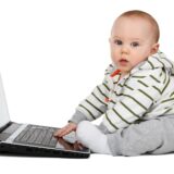 ノートパソコンを触って横を観てる赤ちゃん