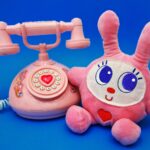 ピンクの電話の隣にウサギのぬいぐるみがある
