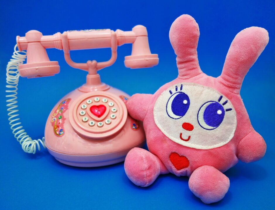 ピンクの電話の隣にウサギのぬいぐるみがある