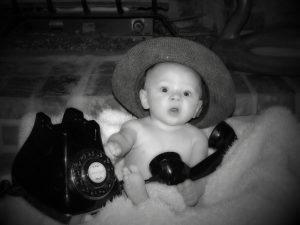 黒い固定電話で遊んでびっくりする赤ちゃん