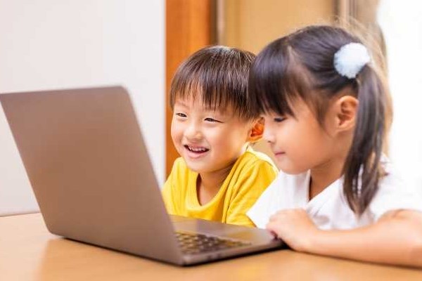 オンライン英会話学習する子ども2人がパソコンを覗いてます